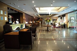 A hotel lobby with a reception desk, seating area, and a decorative fountain. - Ramee Guestline Hotel (Muscat)