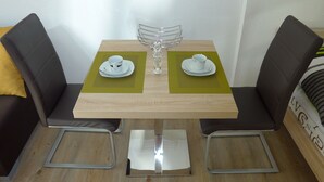 Une petite table à manger avec deux chaises, un vase en verre et deux assiettes blanches accompagnées de tasses.