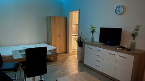 Une chambre moderne comprenant un lit, un bureau, une chaise, une télévision et une armoire.
