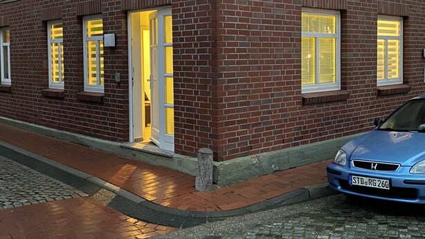Un bâtiment en briques devant lequel est garée une voiture bleue.