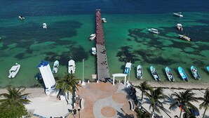 An aerial view of a beach with a pier extending into the ocean, boats docked along the pier, and a sandy beach with palm trees. - Xíinbal House in Puerto Morelos (Puerto Morelos)