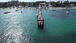 A pier extending into a body of water with several boats and a lighthouse in the background. - Xíinbal House in Puerto Morelos (Puerto Morelos)