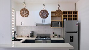 A modern kitchen with white cabinets, a stainless steel refrigerator, a built-in microwave, and a gas stove. - Xíinbal House in Puerto Morelos (Puerto Morelos)
