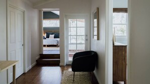 Ein Flur, der zu einem Schlafzimmer mit einem Bett, einem Sessel und einer Tür führt.