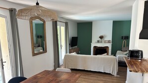A hotel room with a wooden dining table, a bed with a white bedspread, a fireplace, and a television. - Quiet villa with pool close to the sea (Marsillargues)