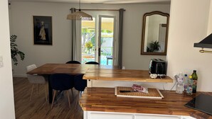 A kitchen with a wooden countertop, a kettle, and a toaster. There is a door leading to an outdoor area with a table and chairs. - Quiet villa with pool close to the sea (Marsillargues)