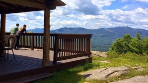 A wooden deck with a railing overlooking a mountainous landscape.