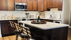 A modern kitchen with wooden cabinets, stainless steel appliances, and a central island with bar stools.