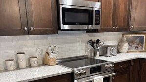 A modern kitchen with dark wood cabinets, stainless steel appliances, and a white tiled backsplash.