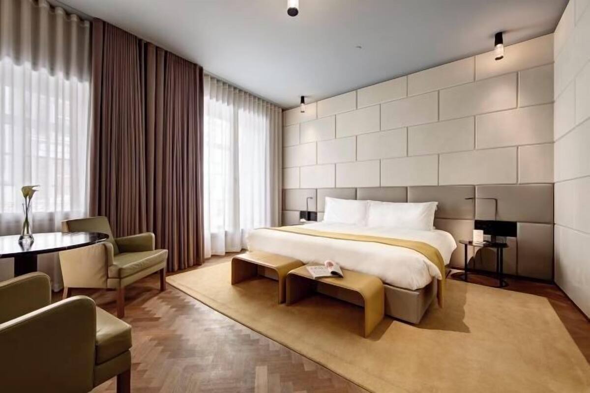 A modern hotel room with a large bed, a small table, and a bench.