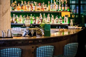 A bar area with a variety of bottles and glasses, a cash register, and a green menu stand. - Hotel Cafe Royal (London)
