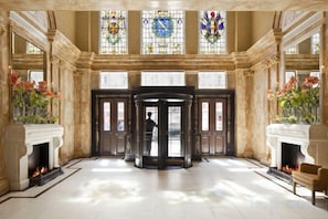 A grand lobby with a central revolving door, large windows, and a fireplace. - Hotel Cafe Royal (London)