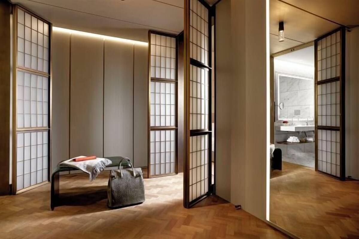 A room with sliding shoji screens, a bench, a handbag, and a glimpse of a bathroom.