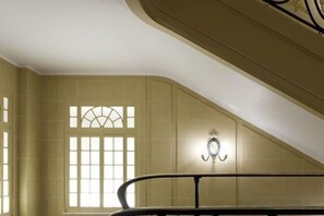 A staircase with a handrail and a wall-mounted light fixture. - Hotel Cafe Royal (London)
