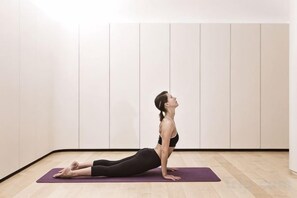 A person performing a yoga pose on a purple mat in a room with white walls and a wooden floor. - Hotel Cafe Royal (London)