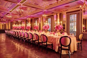 A long banquet table with chairs, set for a formal event, in a room with ornate ceiling and large windows. - Hotel Cafe Royal (London)