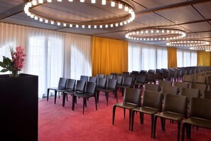 A conference room with rows of chairs, a red carpet, and large windows with curtains. - Hotel Cafe Royal (London)