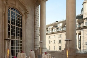 A terrace with tables and chairs, large windows, and classical architecture. - Hotel Cafe Royal (London)