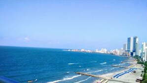 A coastal cityscape with a beach, high-rise buildings, and a clear sky.