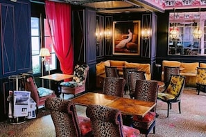 A restaurant with a wooden table, leopard-print chairs, and a red curtain. - JOBO hotel - Joséphine Bonaparte (Paris)