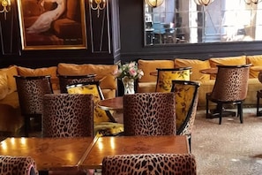 Un espacio de descanso con sofás y sillones, algunos con tapicería de estampado de leopardo, y una mesa con un jarrón de flores.