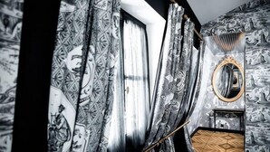 Une pièce avec un papier peint à motifs, un miroir et un plancher en bois.