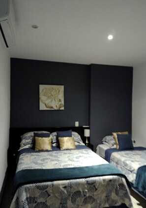 A bedroom with two beds, dark walls, and a ceiling light. - Best Location San Salvador, Escalón, Torre 91. N6 (San Salvador)