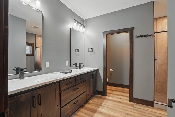 Un baño moderno con un espejo grande, tocador y suelo de madera.