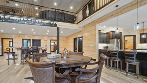 Ein geräumiger Essbereich mit Holztisch und Stühlen, eine Küche mit modernen Geräten und eine Schlafgalerie mit Balkon.