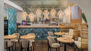 A bar area with round tables and chairs, a marble counter, and hanging light fixtures. - Mamaison Hotel Andrassy Budapest (Budapest)