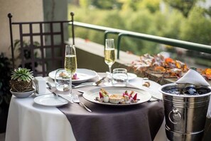 Une table dressée pour un repas, avec une assiette à dessert, deux verres de vin blanc, un petit bol et un seau en métal.