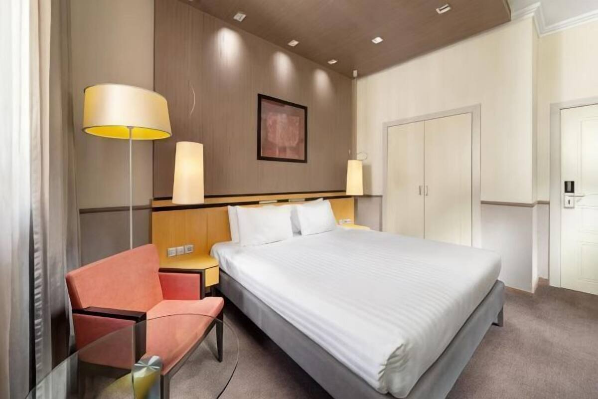 Une chambre d’hôtel comprenant un lit, une chaise, un bureau, une lampe et une armoire.