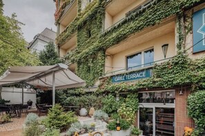 A building with a sign reading 'GRILL TERRACE' and outdoor seating with umbrellas. - Mamaison Hotel Andrassy Budapest (Budapest)