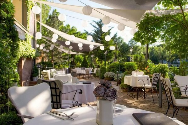An outdoor dining area with tables and chairs, string lights, and greenery. - Mamaison Hotel Andrassy Budapest (Budapest)