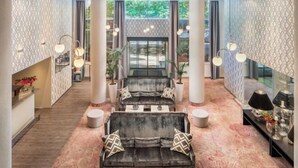 A spacious lobby with a central seating area, large windows, and a patterned wall design. - Mamaison Hotel Andrassy Budapest (Budapest)