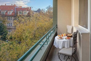 Un balcon avec une table préparée pour le petit-déjeuner, donnant sur un quartier résidentiel où les arbres arborent leurs couleurs automnales.