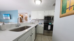 A modern kitchen with white cabinets, stainless steel appliances, and a large sink. - Sugar Beach 2 Bedroom, 2 Bathroom Condo.  4 Pools!  Free Daily Activities! (Orange Beach)
