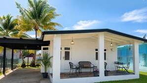 A covered patio with outdoor furniture, palm trees, and a clear sky. - The Blue Coconut • Pool • Pergola • Steps from Boqueron Beach (Boquerón)
