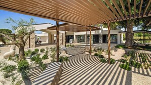 Ein überdachter Außenbereich mit einer Pergola, einem Steinweg und einem großen Baum.