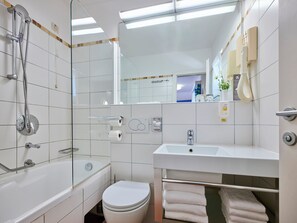 Et moderne badeværelse med badekar, toilet og håndvask.