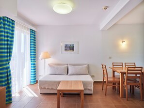 Une chambre à coucher comprenant un lit, une table de chevet, une lampe, ainsi qu’un coin repas avec des chaises et une table.