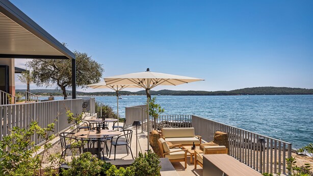 Une terrasse avec des sièges extérieurs, une vue sur la mer et une rambarde.
