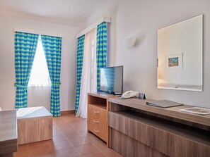 A hotel room with a bed, a desk with a computer, a TV, a phone, and curtains. - Maistra Select Naturist Park Koversada Apartments (Vrsar)