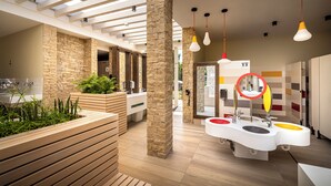 Ein modernes Badezimmer mit einer Holzbank, Steinsäulen und einem farbenfrohen Waschbereich.