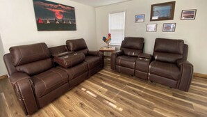A living room with two brown leather sofas, a wooden coffee table, and a framed picture of a sunset. - Base Camp Retreat (Glendo)