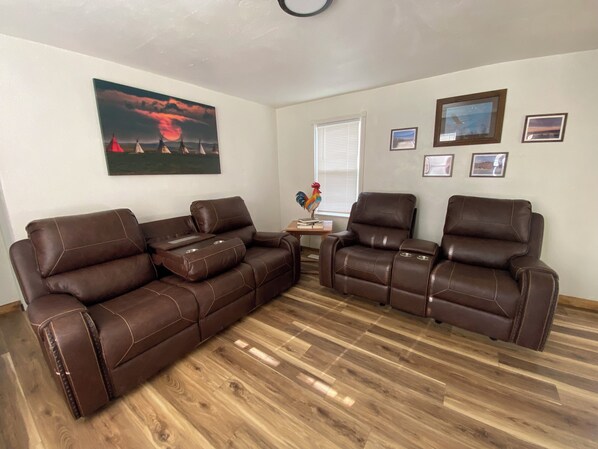 A living room with two brown leather sofas, a wooden coffee table, and a framed picture of a sunset. - Base Camp Retreat (Glendo)