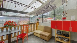 A dining area with a table, chairs, a sofa, and a kitchen area with red cabinets and a shelf. - The Grand Inca View Mansion - Cusco Retreat (Cusco)
