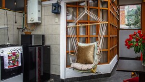 A kitchen with a hanging chair, a stove, and a refrigerator.