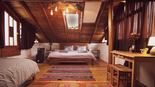A cozy attic bedroom with a large bed, a wooden desk, and a colorful rug. - The Grand Inca View Mansion - Cusco Retreat (Cusco)
