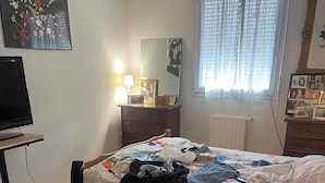 A bedroom with a bed, a dresser, a desk with a computer, a window with blinds, and a rug. - Comfortable apartment (Montpellier)